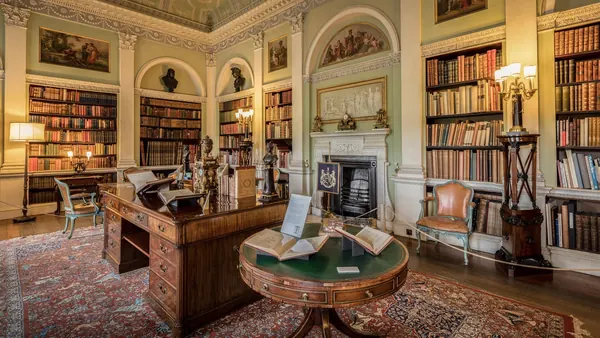 An old library room with tall wooden bookcases full of leather-bound books