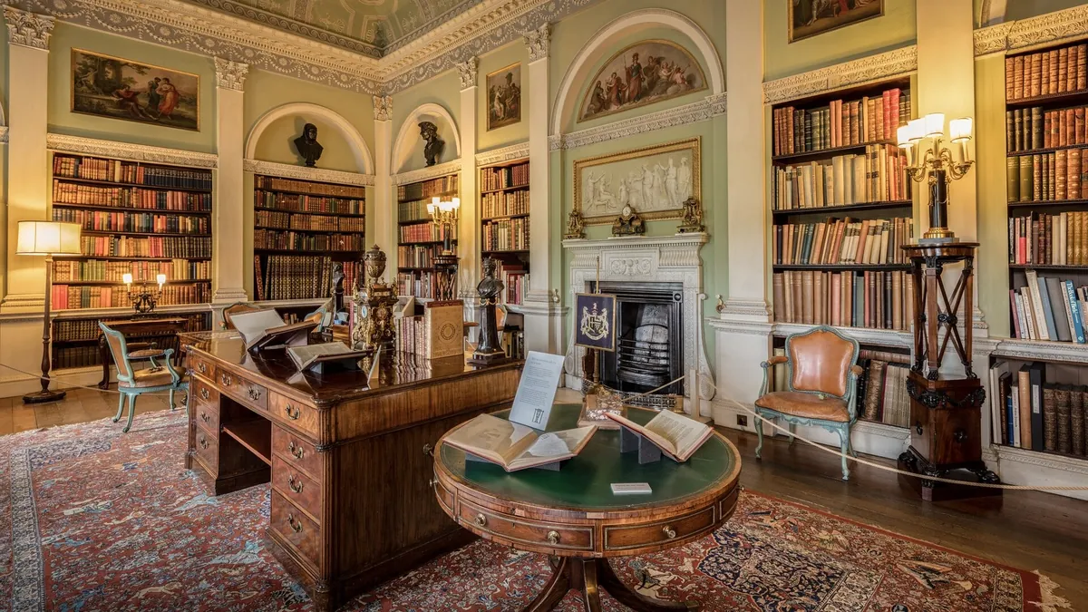An old library room with tall wooden bookcases full of leather-bound books
