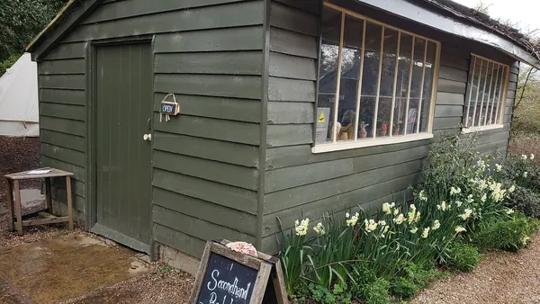 A small second-hand bookshop in a green wooden hut in a garden