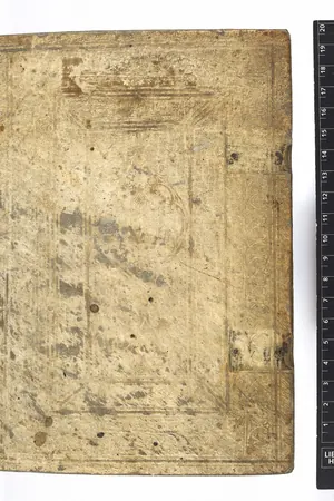 A very old book in a worn vellum binding, photographed beside a colour scale